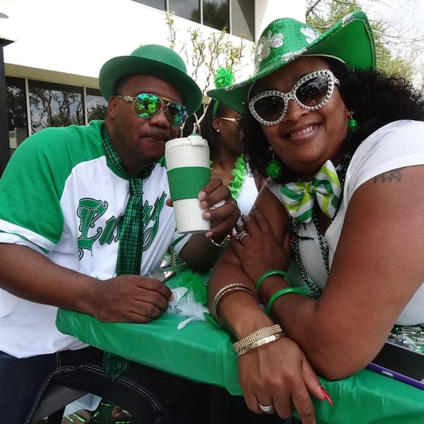 Two people in green and white St. Patrick's Day attire, smiling at the Chicago Bar & Grill.