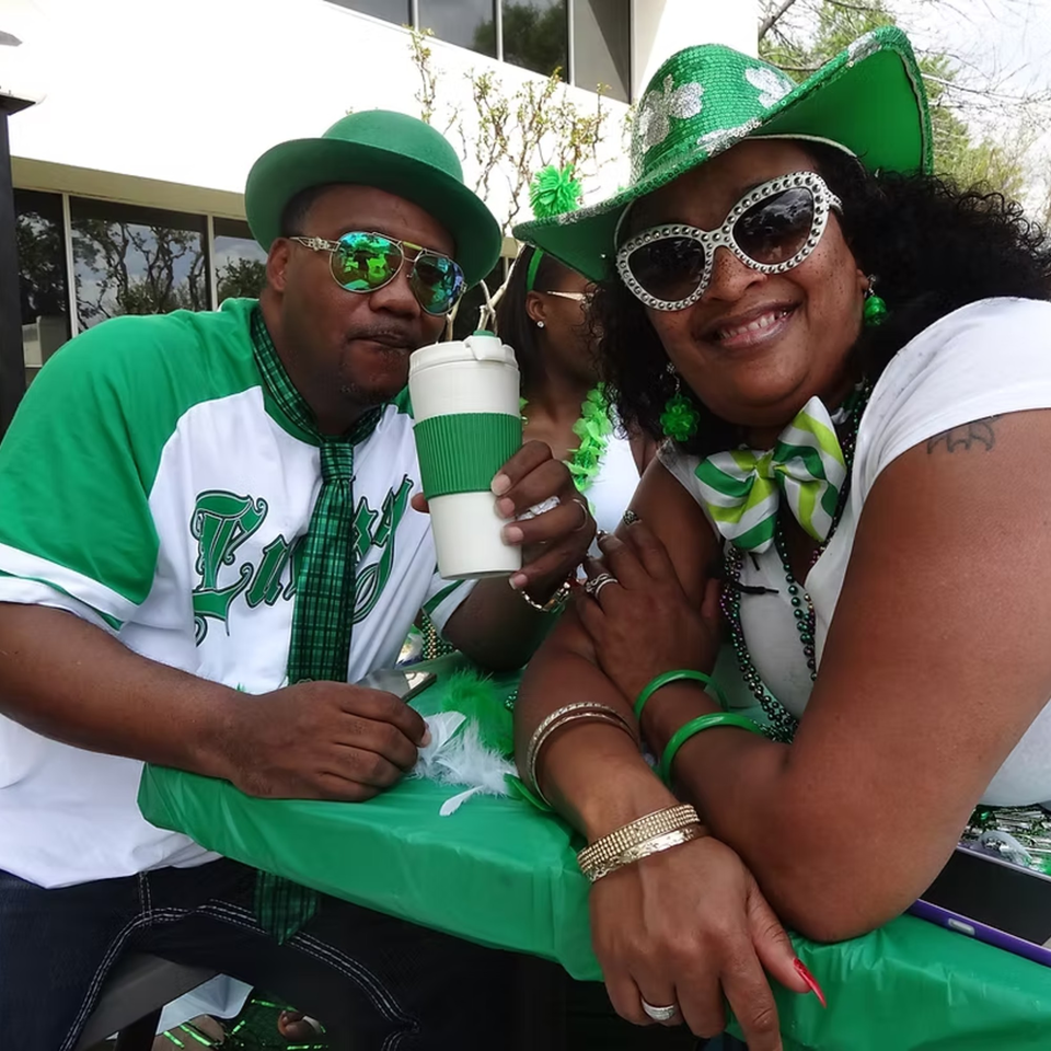 Two people in green and white St. Patrick's Day attire, smiling at the Chicago Bar & Grill.