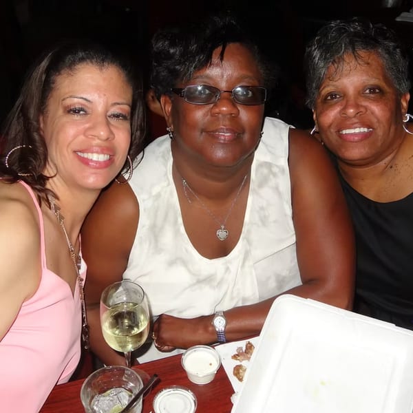 Three smiling women enjoying drinks and food at a table in Chicago Bar & Grill.