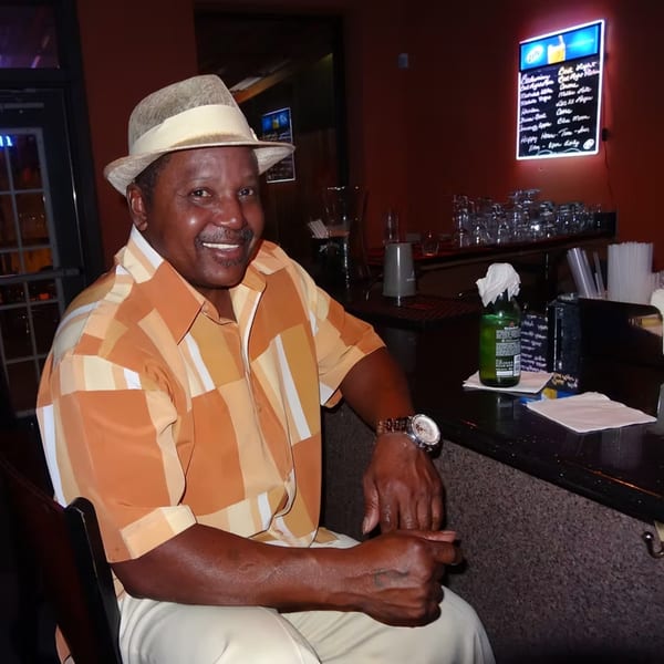 Man in a fedora and patterned shirt smiling at the bar of Chicago Bar & Grill.