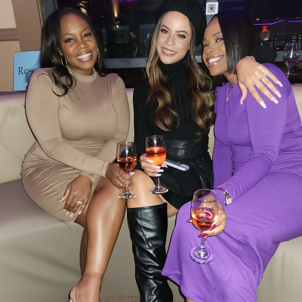 Three smiling women in stylish outfits, holding wine glasses, enjoying a night out at Chicago Bar & Grill.