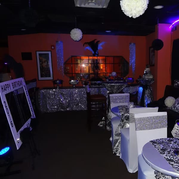 A dimly lit Chicago Bar & Grill interior with orange walls, decorated for a birthday party.