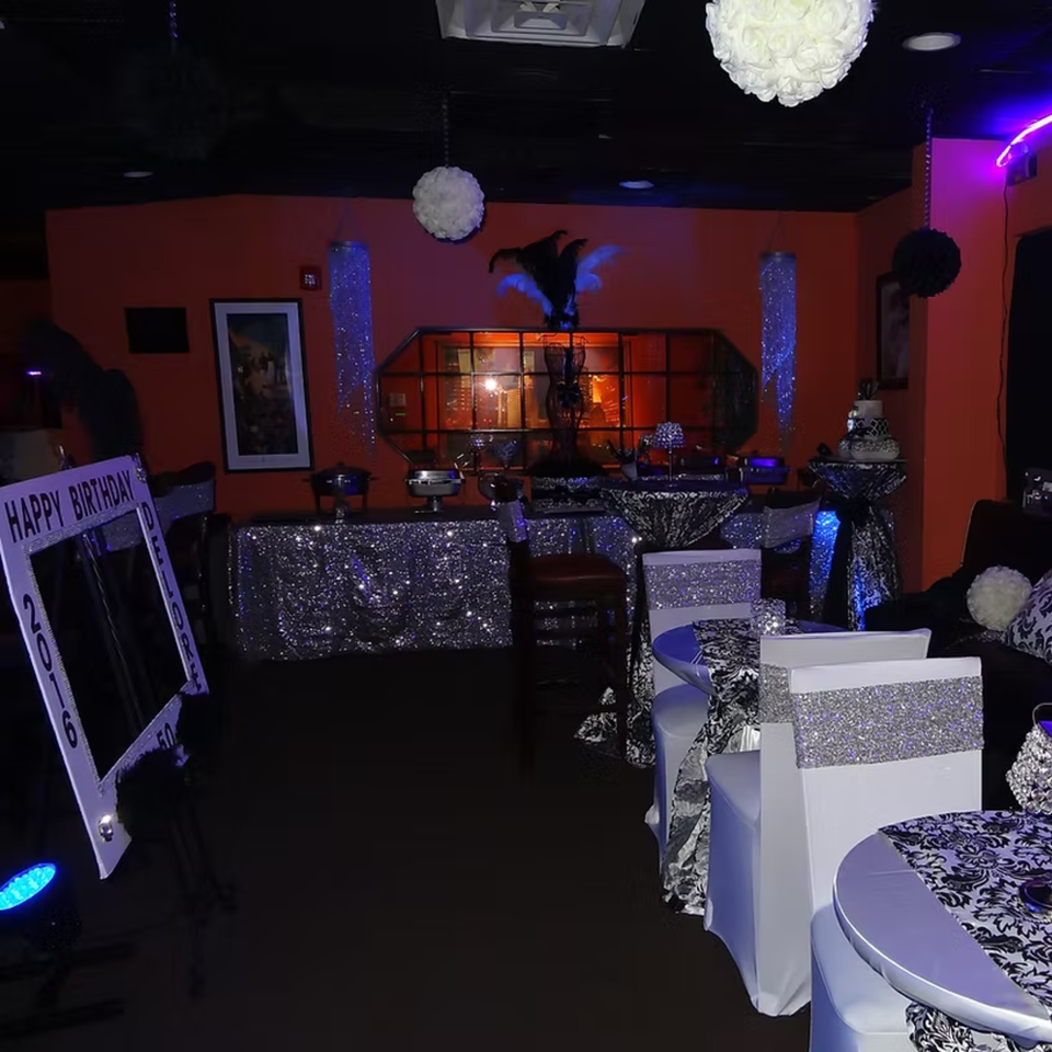 A dimly lit Chicago Bar & Grill interior with orange walls, decorated for a birthday party.