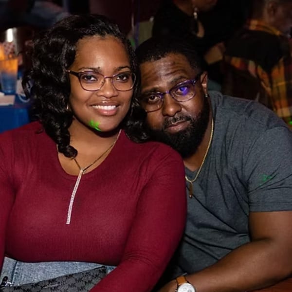 Smiling couple, a woman in red and a man in gray, enjoying themselves at Chicago Bar & Grill.